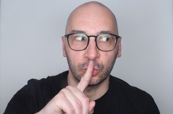 Björn Schulze looking to the side with a finger to his lips.