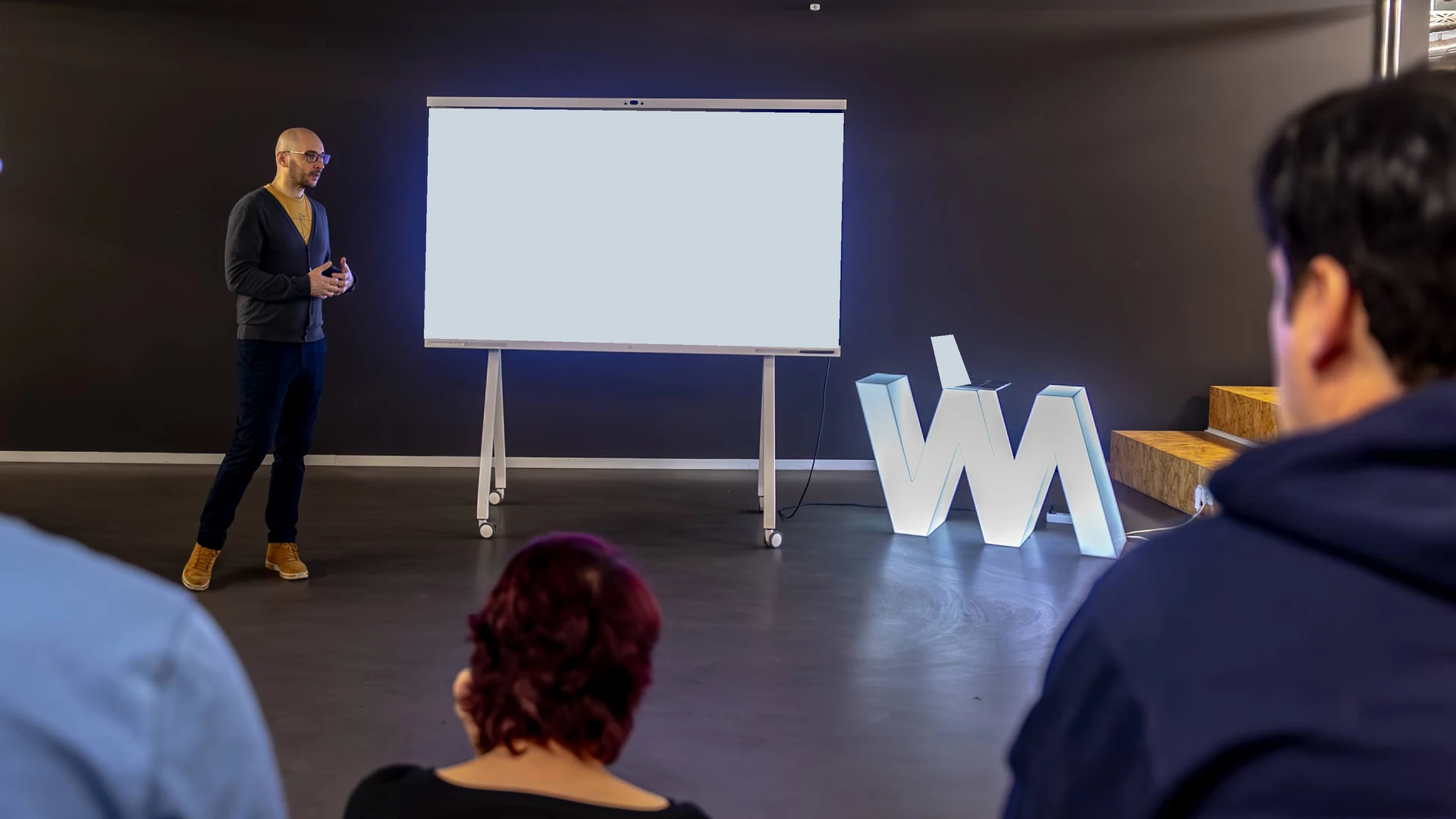 Björn Schulze speaking to a group during a workshop, with a screen behind him.