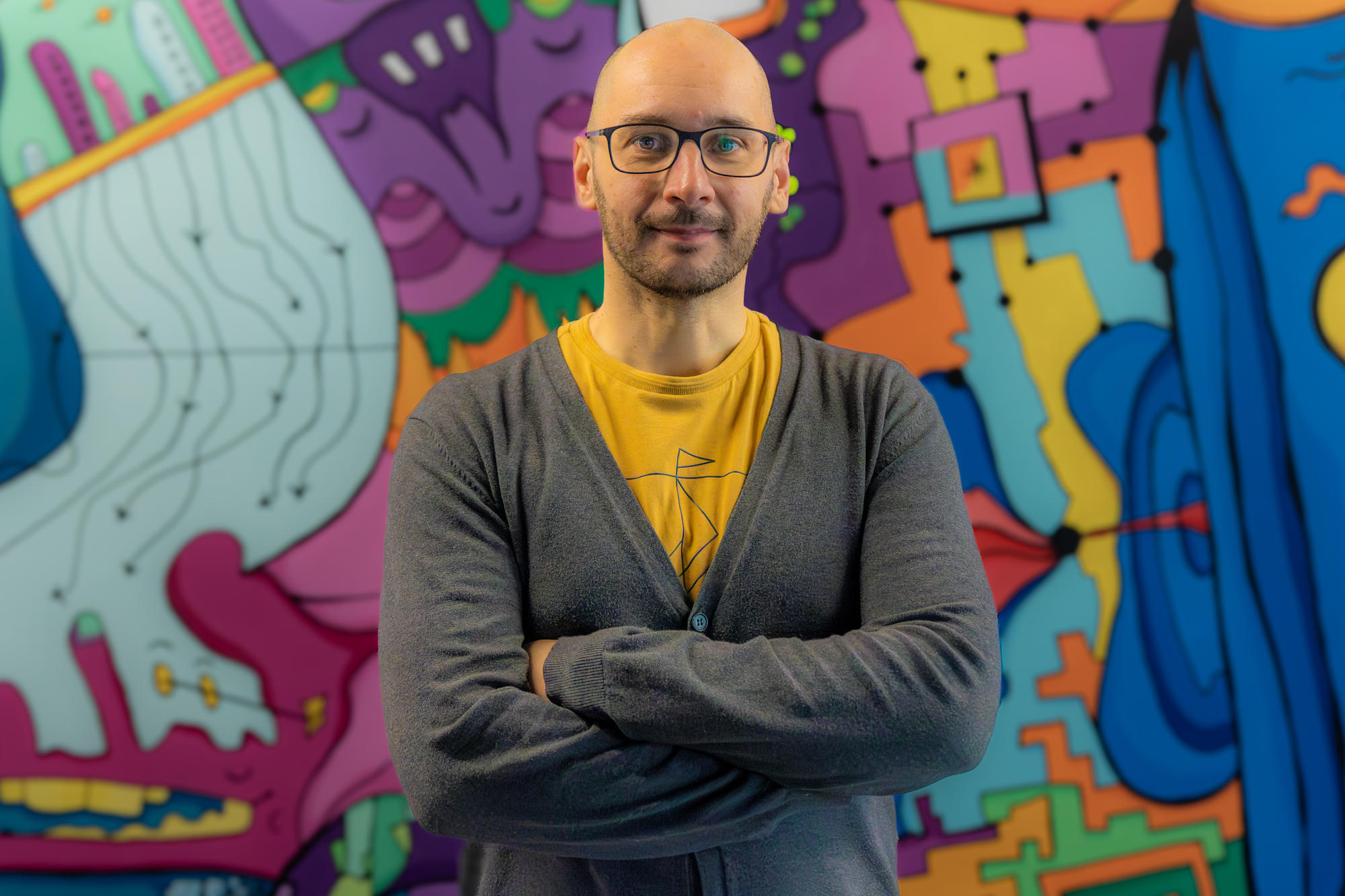 Björn Schulze looking into the camera in front of a colourful mural.